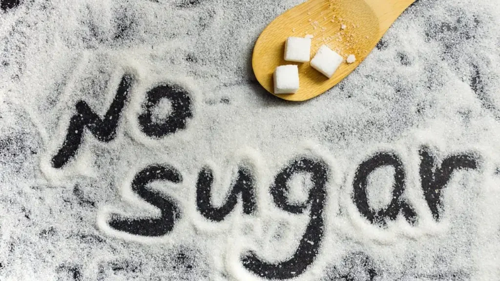 No Sugar लिखा हुआ, दानेदार चीनी पर लकड़ी के चम्मच में चीनी के क्यूब