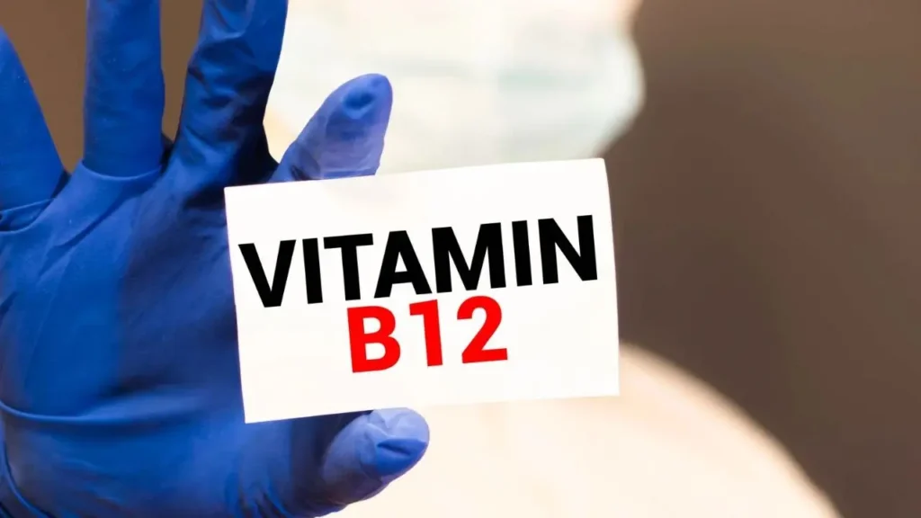 Blue gloved hand holding a card that reads “Vitamin B12”.