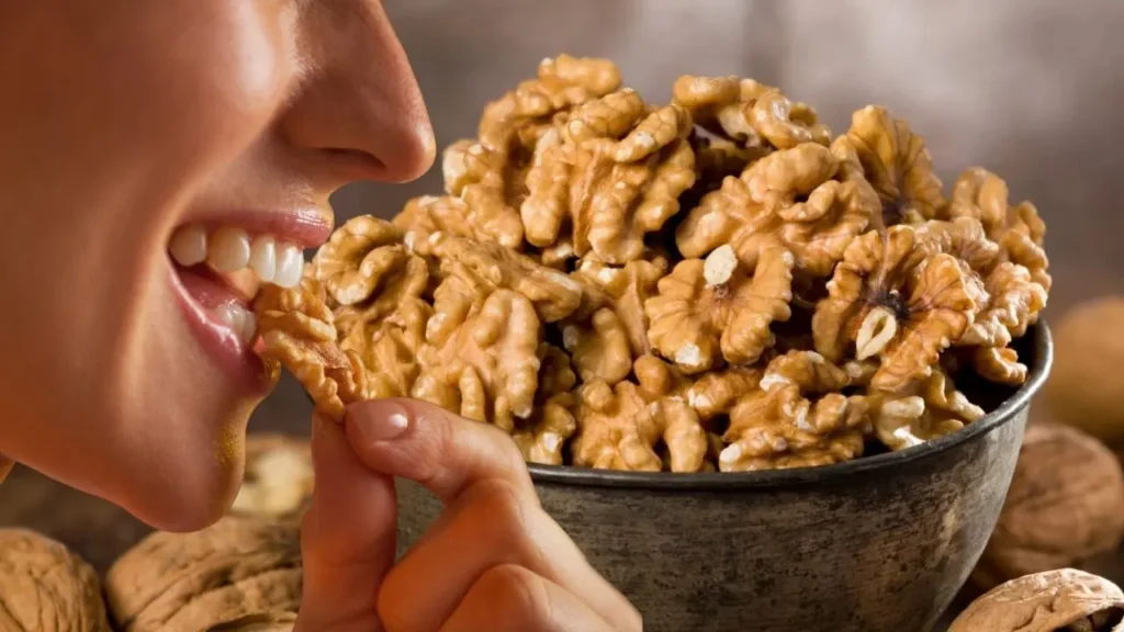 एक महिला अखरोट खाते हुए दिखाई दे रही है और सामने कटोरी में ढेर सारे अखरोट रखे हुए हैं — सर्दियों में हेल्दी स्नैक का क्लोज-अप।