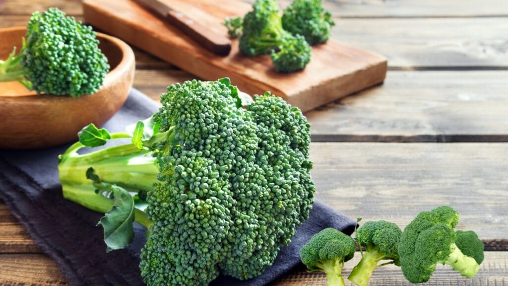 ताज़ी हरी ब्रोकली के फूल और डंठल लकड़ी की टेबल पर रखे हुए