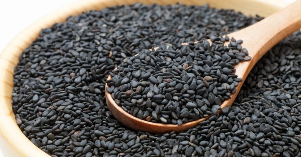 काला तिल के दाने लकड़ी के चम्मच और कटोरे में भरे हुए