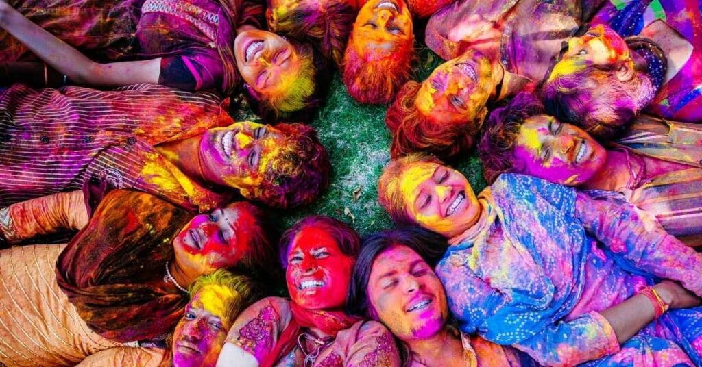 होली खेलते हुए रंगों से सराबोर खुश लोग, जो एक साथ लेटकर होली का त्योहार खुशी और उत्साह के साथ मना रहे हैं