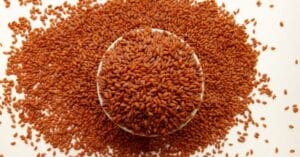 कटोरी में रखे हुए लाल रंग के Halim Seeds (Garden Cress Seeds) का क्लोज़-अप दृश्य।